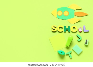 Back to school creative flat lay with paper rocket, colorful letters, sticky note and stationery on bright green background with copy space