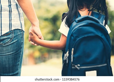 Back to school. Cute asian pupil girl with backpack holding her mother hand and going to school in vintage color tone