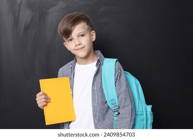 Back to school. Cute boy holding book near chalkboard - Powered by Shutterstock