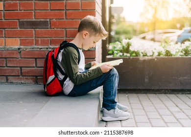 Back To School. Cute Child With Backpack, Holding Notepad And Training Books. School Boy Pupil With Bag. Elementary School Student Going To Classes. Kid Sitting On Stairs Outdoors At Brick Wall.