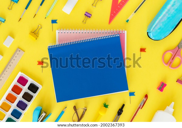 Back to school. Education concept. Everything for
school and office. School supplies. Pens, pencils, notebook,
glasses and everything for study on a yellow background. Flatly.
From above.