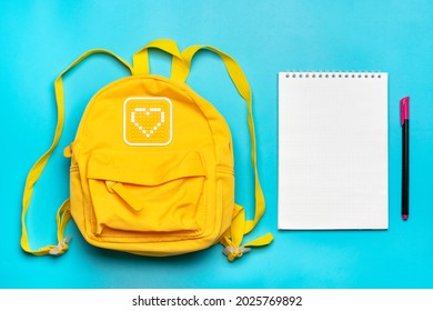 Back to school, education concept. Yellow backpack with school supplies Notebook, pens, ruler, calculator, scissors, tablet isolated on blue background Top view Copy space Flat lay composition Mock up