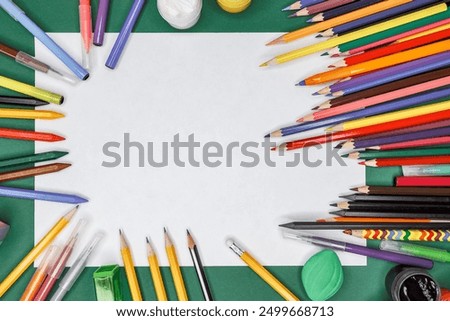 Back to School, Education, Learning Concept. A white blank A4 sheet with school supplies colored multi-colored pencils pens, erasers and sharpeners green background. Top view mockup space for text