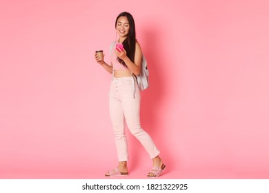 Back To School, Education And Lifestyle Concept. Full Length Of Beautiful Young Asian Female Student Hurry For Classes, Drinking Coffee On Her Way And Using Mobile Phone Over Pink Background