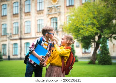 Back to school and education. Little boy kissing girl on the cheek, but girl stop him. No kissing. Social distancing concept. Little students with backpack and notebook.