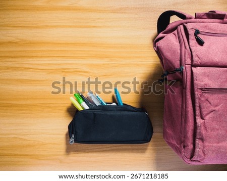 Back to school flat lay. A clean top down view of a backpack and pencil case on a wooden desk with copy space.Ready for class.An organized flat lay of a student's essentials.
