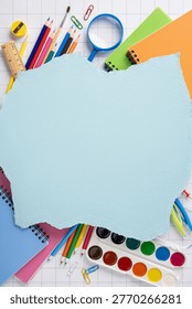 Back to school flat lay featuring colorful school supplies, notebooks, watercolor paints and art tools arranged on a torn paper background for creative projects