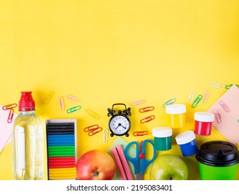 Back To School Flat Lay. Set Of Stationery Supplies, Apples, Water Bottle, Paper Cup And Alarm Clock On Yellow Background. Colorful Composition With Copy Space