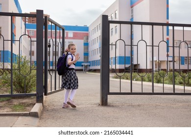 Back To School. Girl In School Uniform Go To School With Backpack Behind Their Backs. Kid Waving Her Hand Saying Bye. Beginning Of Lessons. First Day Of Autumn. Elementary School Student. 