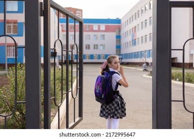 Back To School. Girl In School Uniform Go To School With Backpack Behind Their Backs. Kid Waving Her Hand Saying Bye. Beginning Of Lessons. First Day Of Autumn. Elementary School Student. 