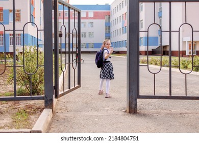 Back To School. Girl In School Uniform Go To School With Backpack Behind Their Backs. Kid Waving Her Hand Saying Bye. Beginning Of Lessons. First Day Of Autumn. Elementary School Student. 