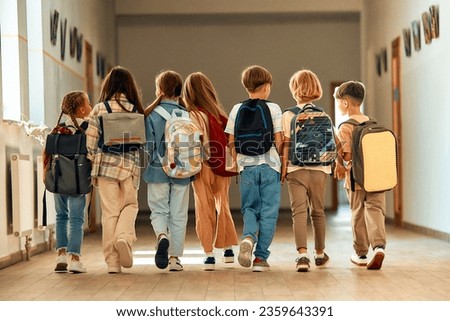 Back to school. A group of schoolchildren with backpacks walk along the school corridor during recess. Education and science concept.