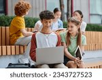 back to school, happy boy and girl using gadgets near school, teenage students outdoors, e-study