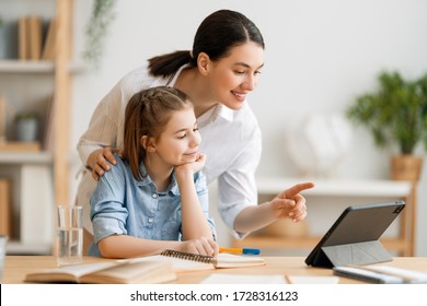 Back To School. Happy Child And Adult Are Sitting At Desk. Girl Doing Homework Or Online Education.