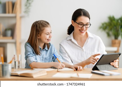 Back To School. Happy Child And Adult Are Sitting At Desk. Girl Doing Homework Or Online Education.