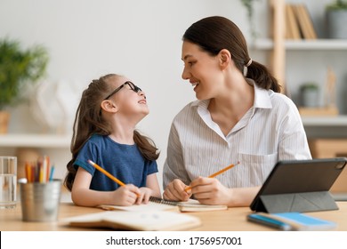 Back To School. Happy Child And Adult Are Sitting At Desk. Girl Doing Homework Or Online Education.