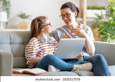 Back To School. Happy Child And Adult Are Sitting On Sofa. Girl Doing Homework Or Online Education.