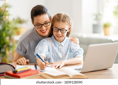 Back To School. Happy Child And Adult Are Sitting At Desk. Girl Doing Homework Or Online Education.