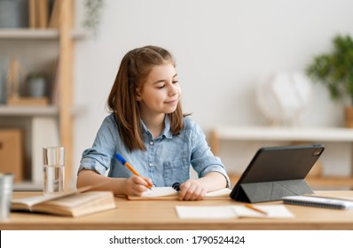 Back To School. Happy Child Is Sitting At Desk. Girl Doing Homework Or Online Education.