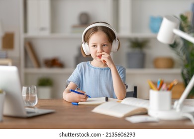 Back to school. Happy child is sitting at desk. Girl doing homework or online education. - Shutterstock ID 2135606293