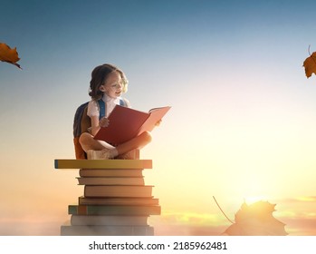 Back to school! Happy cute industrious child sitting the tower books background sunset sky  Concept education   reading  The development the imagination 
