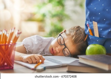 Back to school! Happy cute industrious child is sitting at a desk indoors. Kid is learning in class. Girl is tired and sleeps. - Powered by Shutterstock