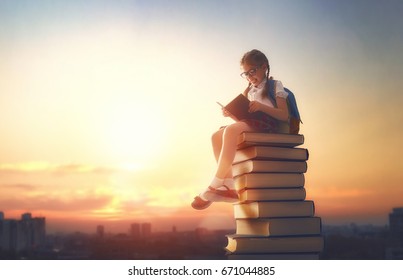 Back to school! Happy cute industrious child standing on books on background of sunset urban landscape. Concept of education and reading. The development of the imagination. - Shutterstock ID 671044885