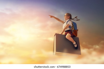 Back to school! Happy cute industrious child flying on the book on background of sunset sky. Concept of education and reading. The development of the imagination. - Shutterstock ID 674988853