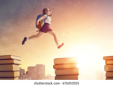 Back To School! Happy Cute Industrious Child Running And Jumping On Books On Background Of Sunset Urban Landscape. Concept Of Education And Reading. The Development Of The Imagination.