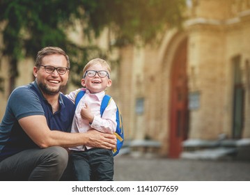 Back To School. Happy Father And Son Go To Elementary School. Parent Taking Child To Primary School. Pupil Go Study With Backpack. Beginning Of Lessons. First Day Of Fall.