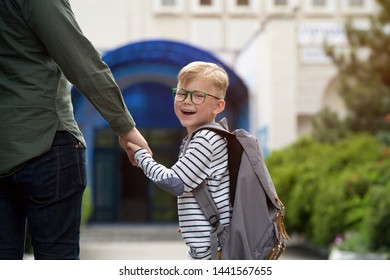 Back To School. Happy Father And Son Go To Elementary School. Parent Taking Child To Primary School. Pupil Go Study With Backpack. Beginning Of Lessons. First Day Of Fall.