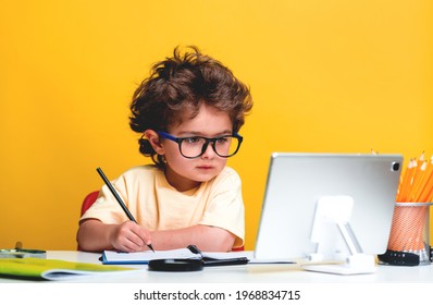 Back To School. Happy Little Pupil Drawing At The Desk. Child Doing Homework With Tablet Computer. Alarm Clock, Pencils, Books. Kid Boy From Primary School. First Day Of Fall.