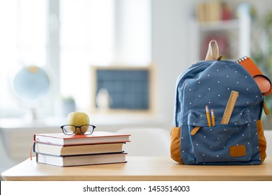 Back To School And Happy Time! Apple, Pile Of Books And Backpack On The Desk At The Elementary School. 