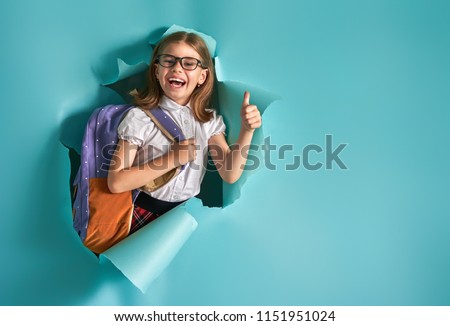 Back to school and happy time! Cute industrious child is breaking through color paper wall. Kid with backpack. Girl ready to study.
