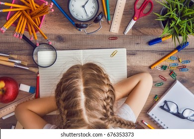 Back to school and happy time! Wooden desk with supplies. A child writes in an empty notebook. Top view.  - Powered by Shutterstock