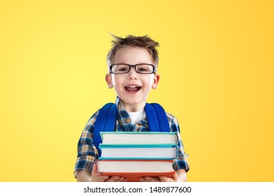 Back To School. Industrious Child Boy With Backpack And Books. Happy Kid Is Breaking Paper Wall. Funny Pupil In Glasses Pointing Up