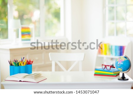 Back to school. Kids bedroom with wooden desk, books, globe, backpack, glasses and pencils. White room with big window for young child. Home interior for girl or boy. Table for homework and study.