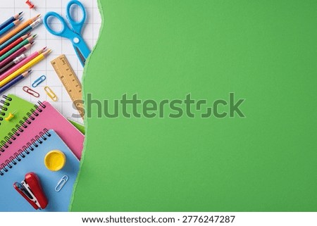 Back to school layout featuring colorful notebooks, pencils, scissors and other stationery on torn green paper for education, study, creativity and classroom promotion