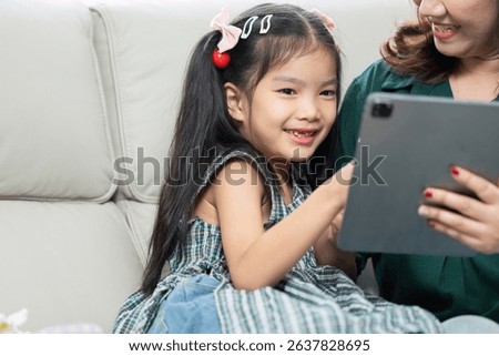 Back to School and Learning Together. A young girl and her mother engage in educational activities using a tablet.