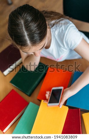 Back to school library concept. Student girl holding book on her head on the background of bookshelves in the library. Education and school concept