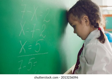 Back To School. Little Schoolgirl Has A Problem With A Math Problem On A School Board In The Classroom. Upset Child Thinks In Class