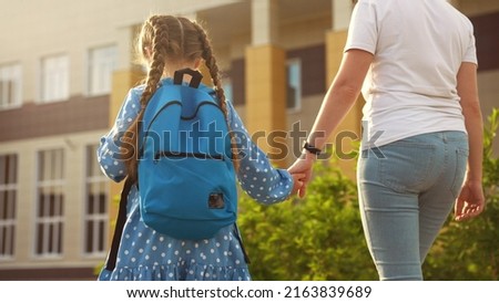 back to school. mom and daughter a go hand in hand to school for lesson. education training support concept sun. child walk to school with a backpack. daughter and mom rush to school. family day