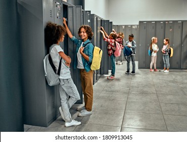 Back to school. Multiracial pupils of primary school in dressing room near personal lockers. Children are ready to study - Powered by Shutterstock