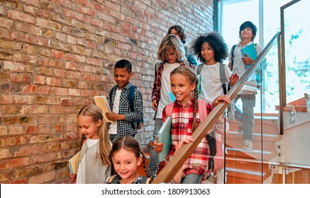 Back to school. Multiracial pupils of primary school in school hall on stairs. Children are ready to study - Powered by Shutterstock