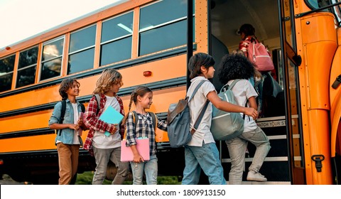 Zurück zur Schule. Mehrrassige Schüler der Grundschule nahe dem Schulbus. Fröhliche Kinder, die bereit zum Lernen sind.