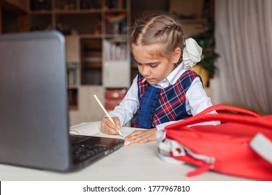 Back to school, new normal education. Cute girl in school uniform writing with pencil during online lesson. Social distance learning and new guidance - Shutterstock ID 1777967810