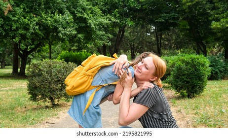 Back To School. Parent And Little Kid Pupil Of Elementary School. Woman And Girl With Backpack Behind Back. Beginning Of Lessons. First Day Of Fall. Mother Hugging Her Daughter In The Park