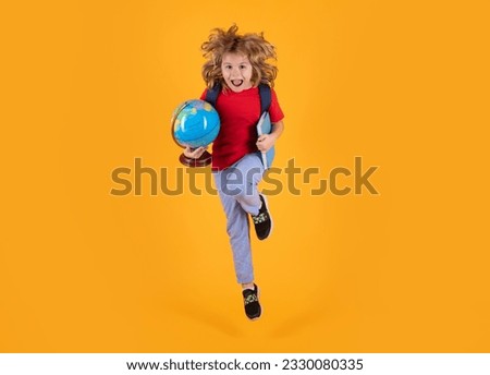 Back to school. Photo of excited little school jumping holding book, empty space isolated yellow background. Amazed school child jump with backpack. Learning and knowledge.