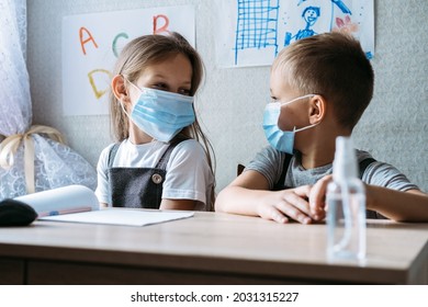 Back To School Safety. Schoolkids wearing masks and using antiseptic in classroom at school. hildren with face mask at school after covid-19 quarantine and lockdown