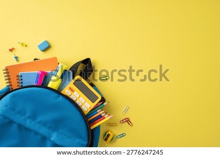 Back to school scene with a blue backpack packed with colorful notebook, pencil, calculator and stationery on a bright yellow background